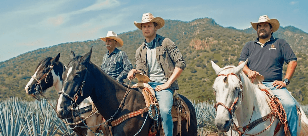 Three men sit on horses in front of mountains.