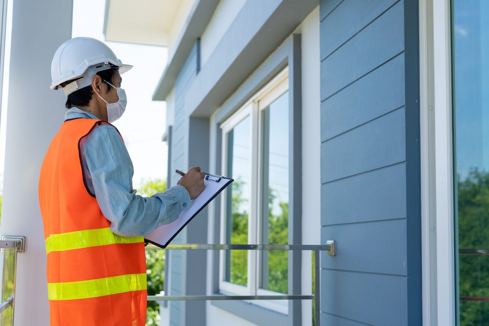 A man with a clipboard inspects a house.