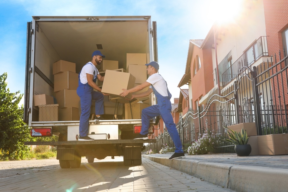 Two workers unload boxes from a box truck.