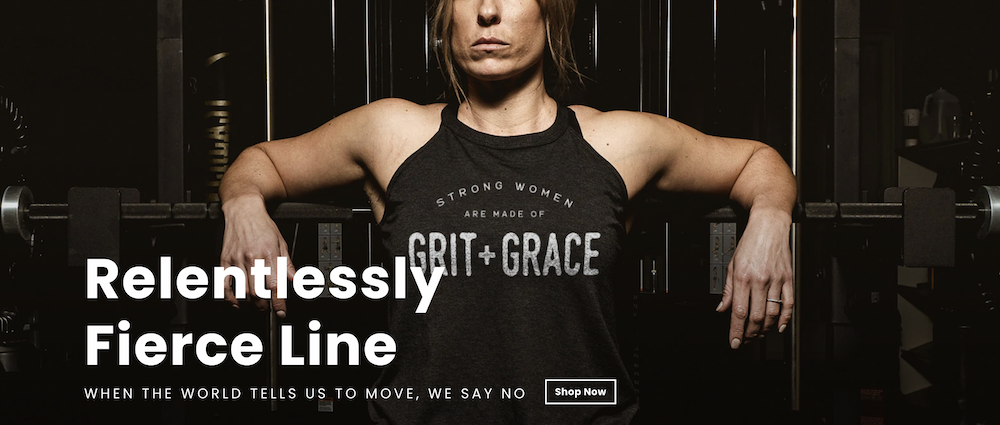 A physically fit woman leans back against a squat bar wearing a t-shirt that says "Grit Grace."