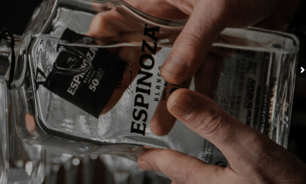 A man's hands hold a bottle of Tequila Espinoza Blanco.