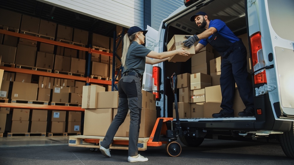 Two men load boxes into a box truck. 