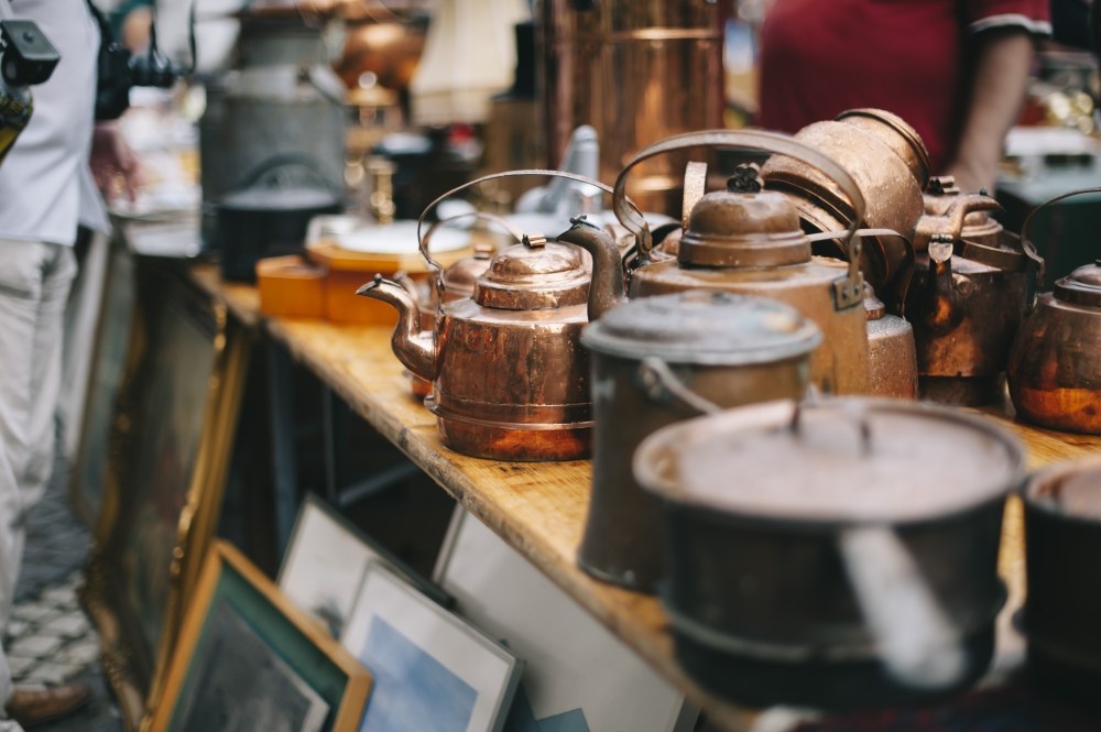 Various antique pots, pans, and paintings at a marketplace