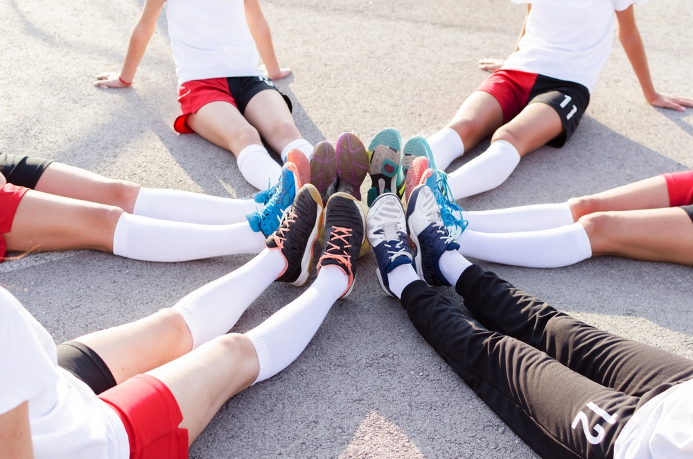 Six people sit in a circle showing off their long. white athletic socks.