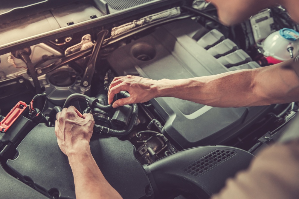 you man fixing mechanical components in a car engine so he can flip the car for a profit.