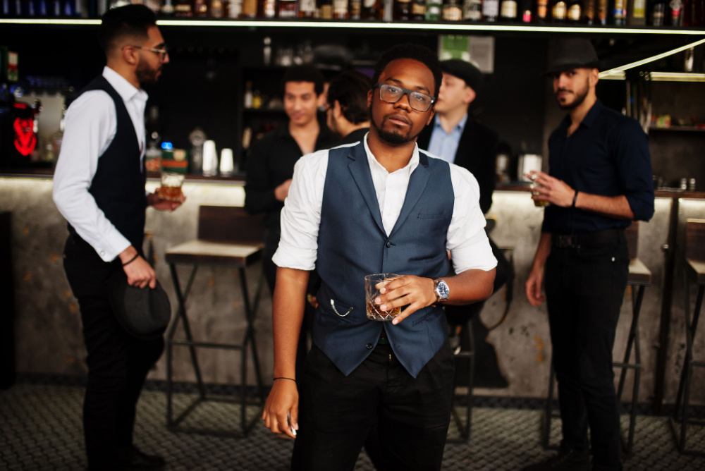 young black man drinking craft whiskey in a hipster bar