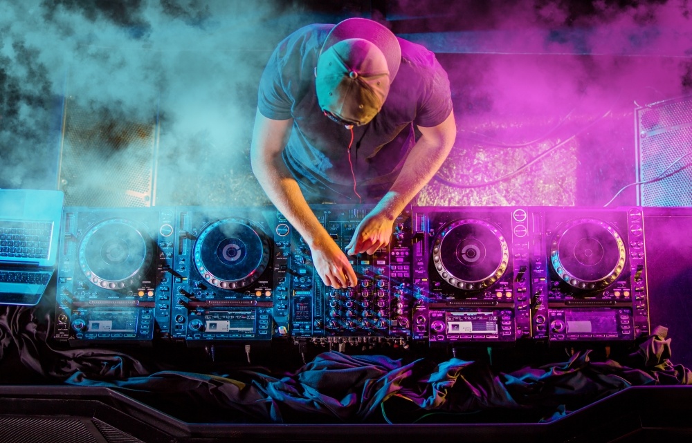 DJ working in a club with blue and pink lights, possibly for gender reveal party