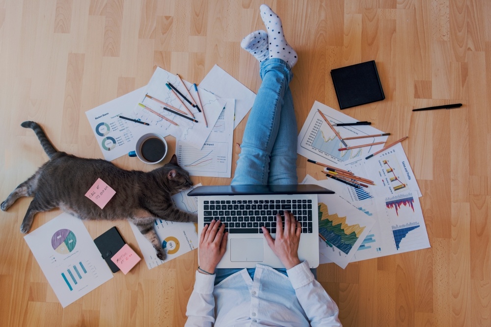 woman sitting on floor with with many papers and a coffee cup working creatively